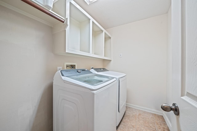 washroom with laundry area, washer and clothes dryer, baseboards, and light tile patterned floors