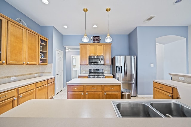 kitchen with visible vents, glass insert cabinets, appliances with stainless steel finishes, light countertops, and a sink