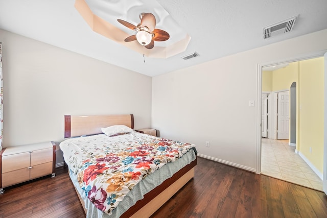 bedroom with arched walkways, dark wood-type flooring, and visible vents