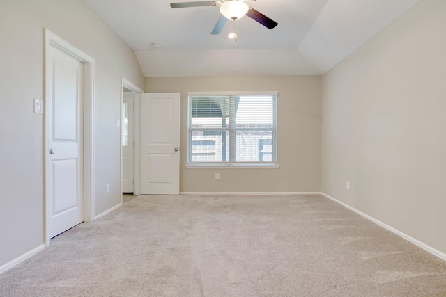 empty room featuring lofted ceiling, light carpet, and baseboards