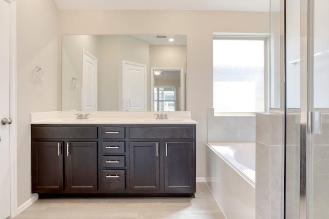 full bath with double vanity, a sink, and a bath