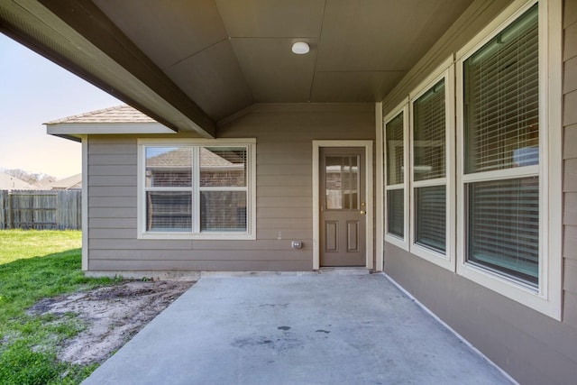 view of exterior entry featuring fence and a patio