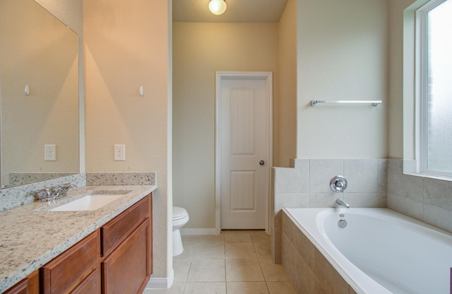 bathroom with tile patterned flooring, vanity, tiled bath, and toilet