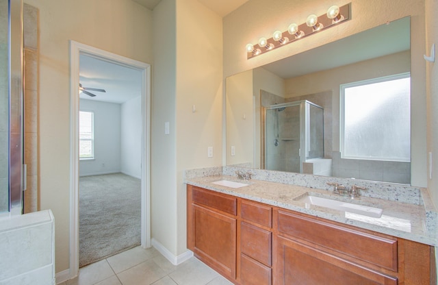 bathroom with tile patterned flooring, vanity, a shower with shower door, and ceiling fan