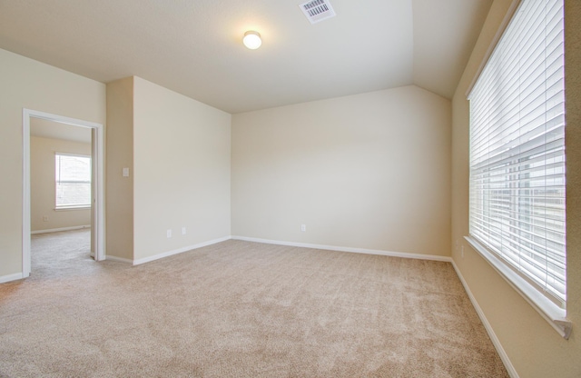 empty room featuring light colored carpet and lofted ceiling