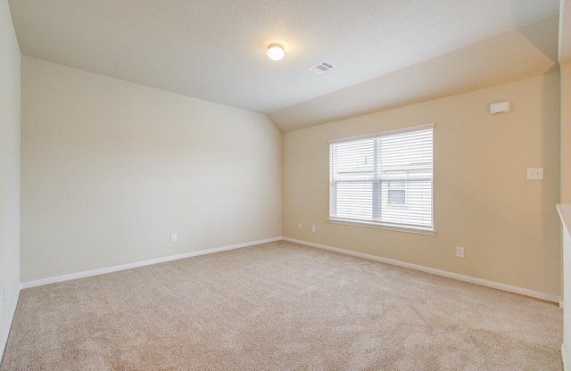 carpeted empty room with lofted ceiling