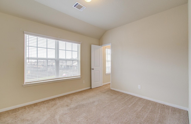 spare room with vaulted ceiling and light colored carpet