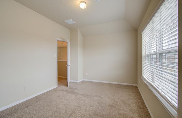 carpeted spare room featuring lofted ceiling