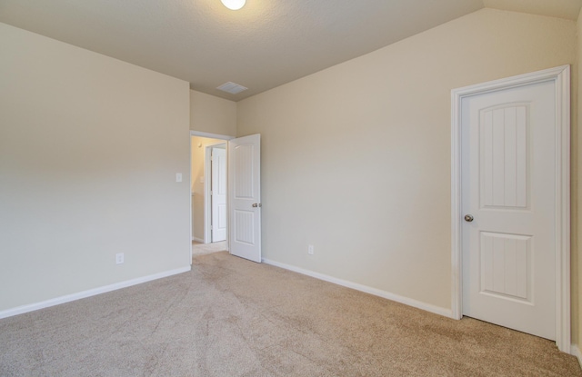 carpeted spare room featuring lofted ceiling