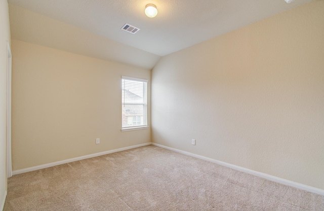 spare room with vaulted ceiling and light carpet