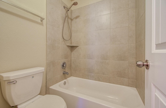 bathroom with tiled shower / bath combo and toilet