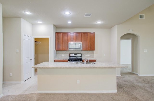 kitchen featuring appliances with stainless steel finishes, sink, an island with sink, and light carpet