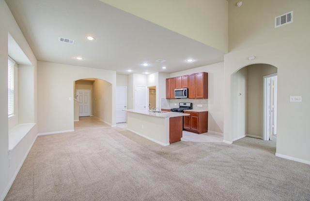 kitchen featuring an island with sink, sink, light carpet, and range with gas cooktop