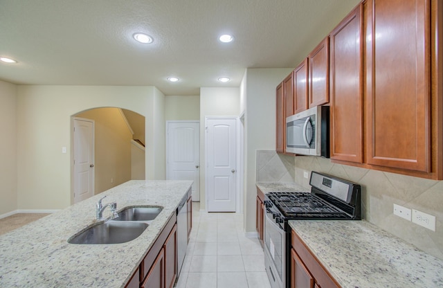 kitchen with tasteful backsplash, light stone countertops, appliances with stainless steel finishes, and sink