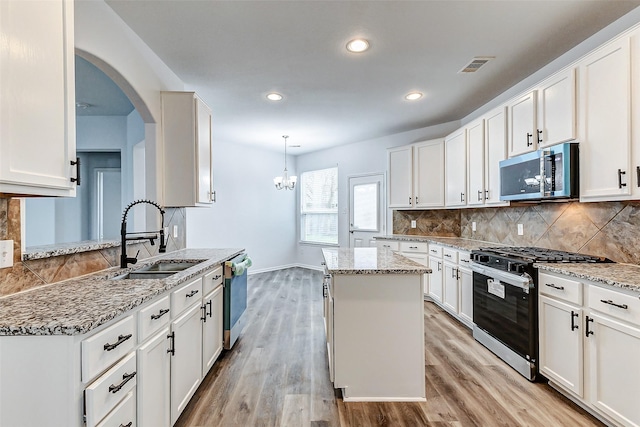 kitchen with stainless steel appliances, white cabinetry, a kitchen island, and sink