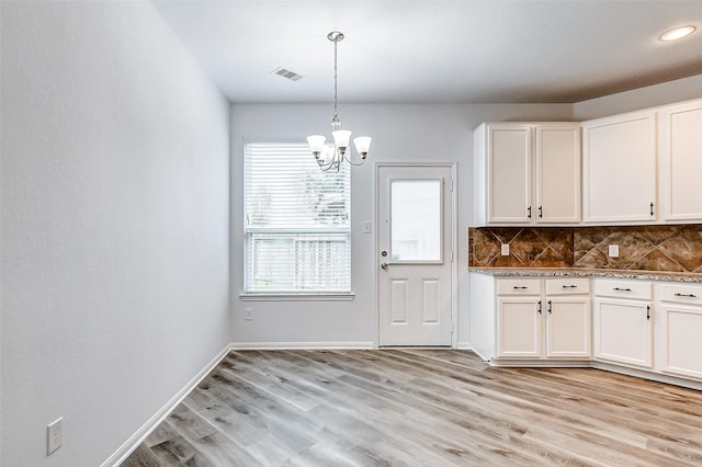 kitchen featuring tasteful backsplash, white cabinets, a chandelier, hanging light fixtures, and light hardwood / wood-style floors