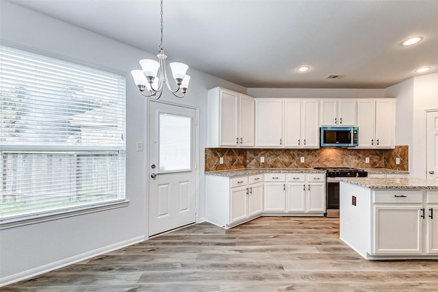 kitchen with stainless steel appliances, light stone countertops, white cabinets, and decorative light fixtures