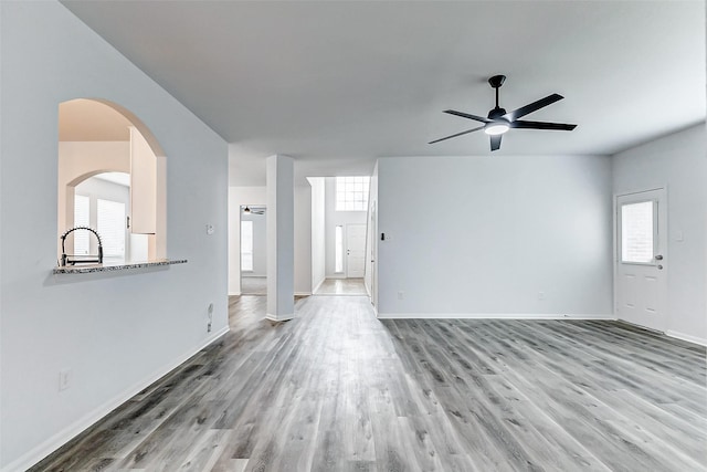 unfurnished living room featuring sink, ceiling fan, and light wood-type flooring