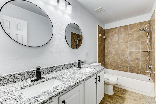 full bathroom with vanity, tiled shower / bath, and toilet