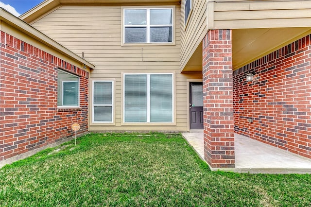 view of exterior entry featuring a lawn