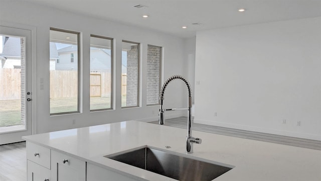 kitchen featuring white cabinetry, sink, a healthy amount of sunlight, and light hardwood / wood-style flooring