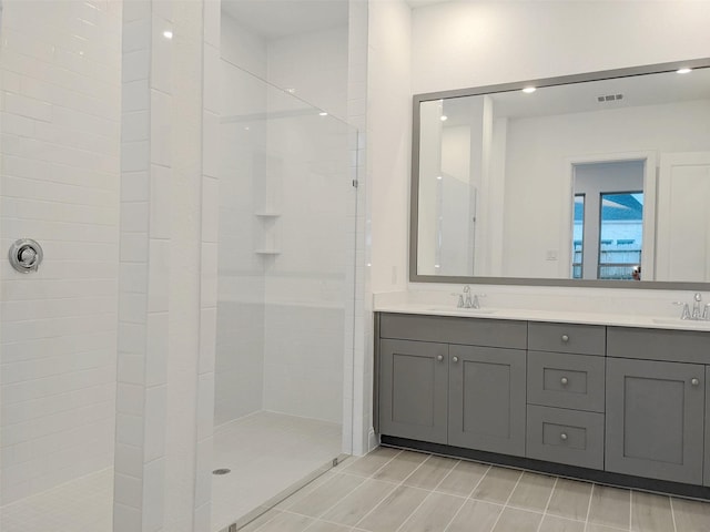 bathroom with vanity, a tile shower, and tile patterned floors