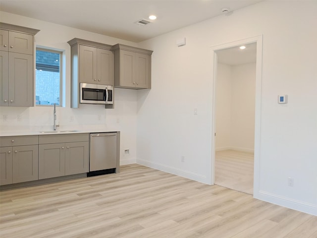 kitchen featuring stainless steel appliances, gray cabinets, sink, and light hardwood / wood-style flooring