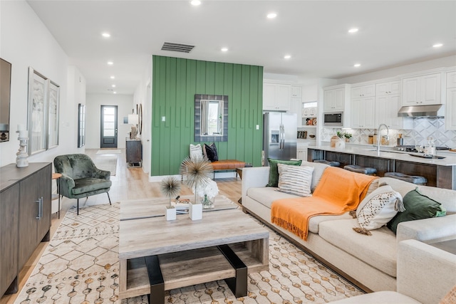 living room featuring sink and light hardwood / wood-style flooring