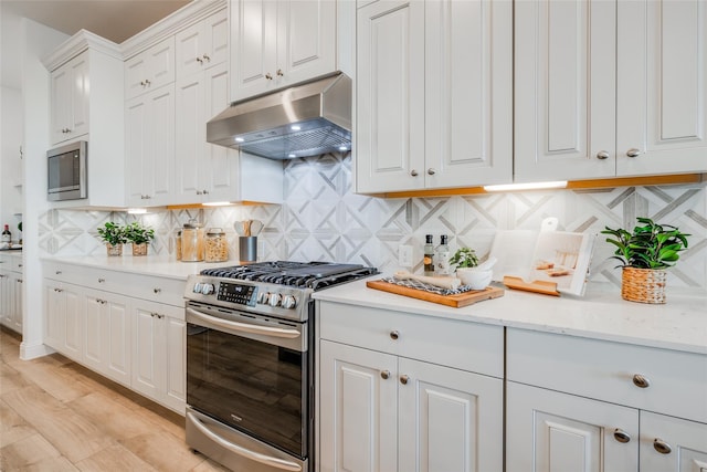 kitchen with white cabinetry, extractor fan, appliances with stainless steel finishes, and decorative backsplash