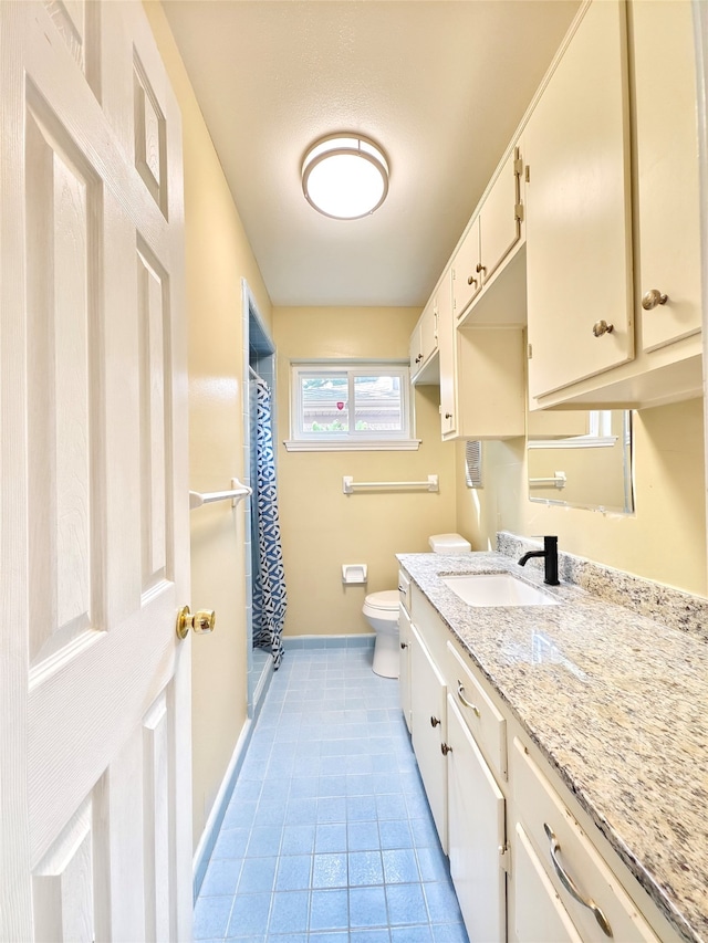 bathroom with a shower with curtain, vanity, toilet, and tile patterned flooring