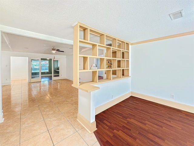 tiled empty room with ceiling fan and a textured ceiling