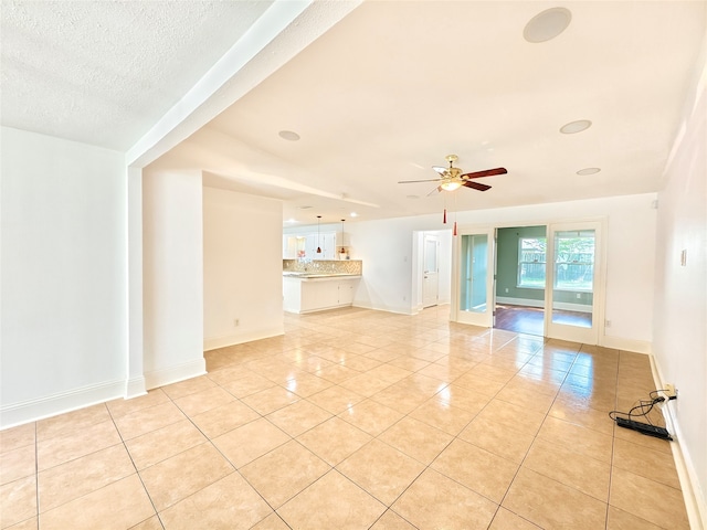 unfurnished living room featuring ceiling fan, a textured ceiling, and light tile patterned floors