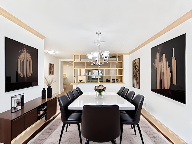 dining space with ornamental molding, a chandelier, and light hardwood / wood-style flooring