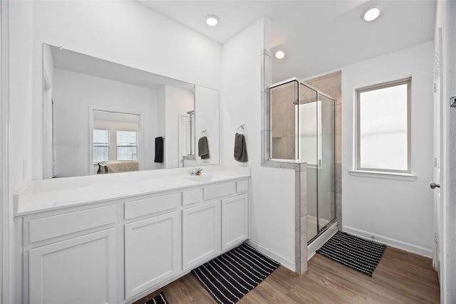 ensuite bathroom featuring a stall shower, baseboards, wood finished floors, ensuite bathroom, and vanity