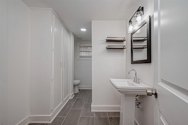 bathroom featuring toilet, baseboards, and wood finish floors