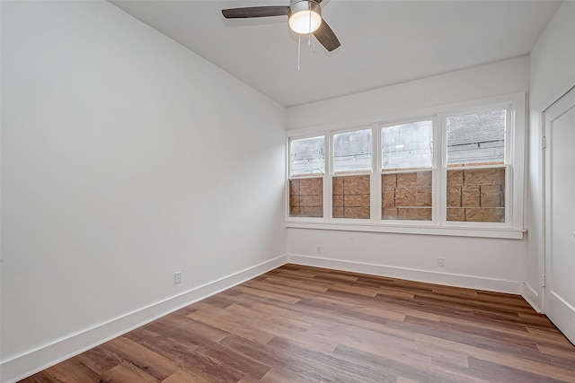 empty room featuring light wood finished floors, baseboards, and a ceiling fan