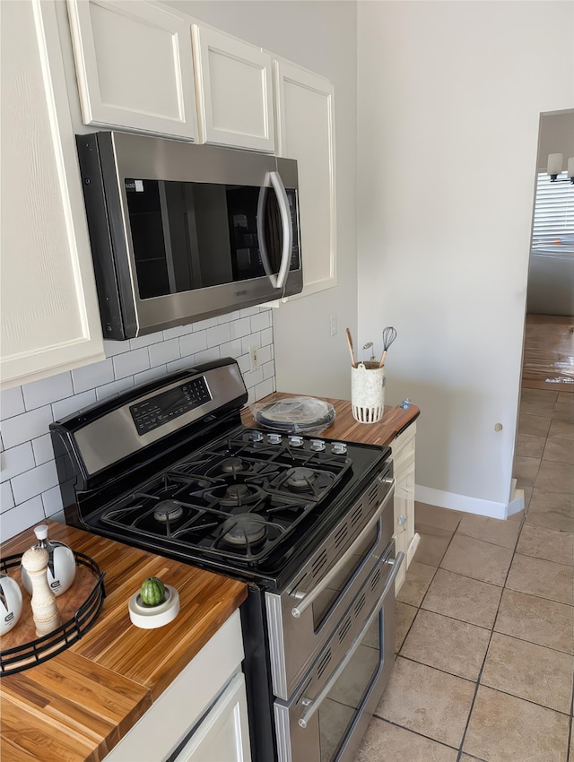 kitchen with white cabinetry, light tile patterned floors, appliances with stainless steel finishes, and wooden counters