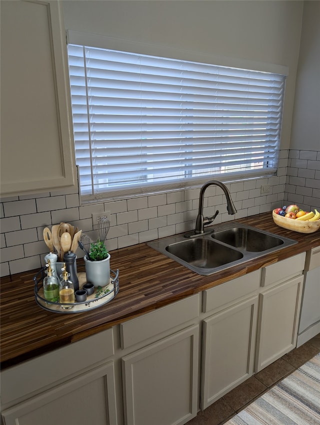 kitchen featuring butcher block countertops, white cabinets, and a sink