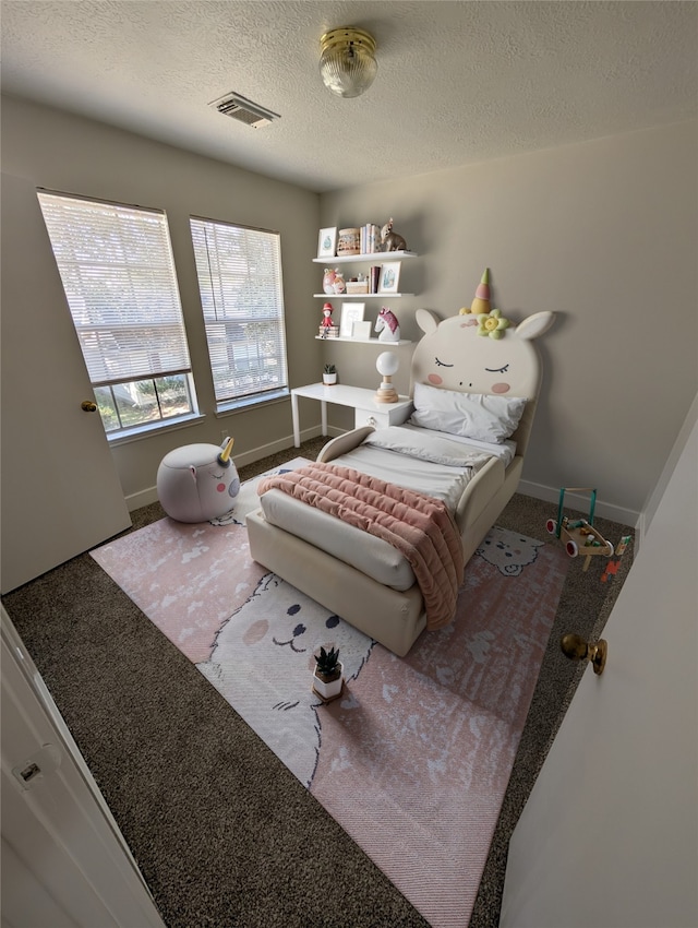 carpeted bedroom featuring visible vents, baseboards, and a textured ceiling