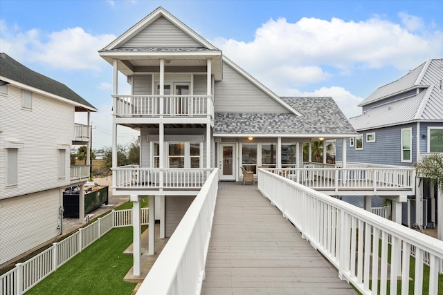 back of house with roof with shingles, a yard, a fenced backyard, and a balcony