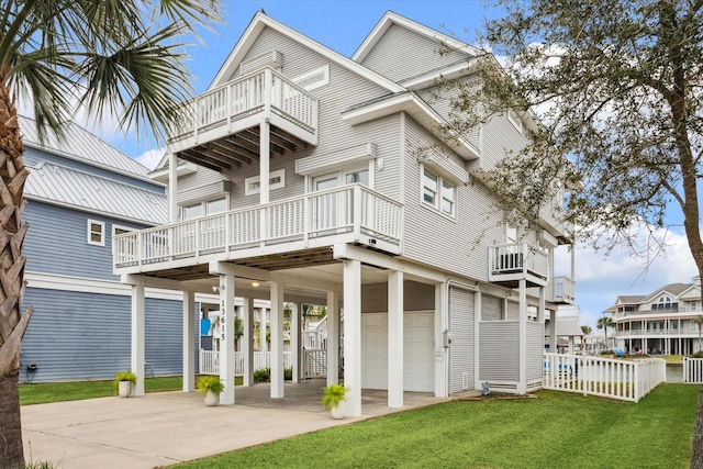 back of property with a balcony, a garage, a carport, and a yard