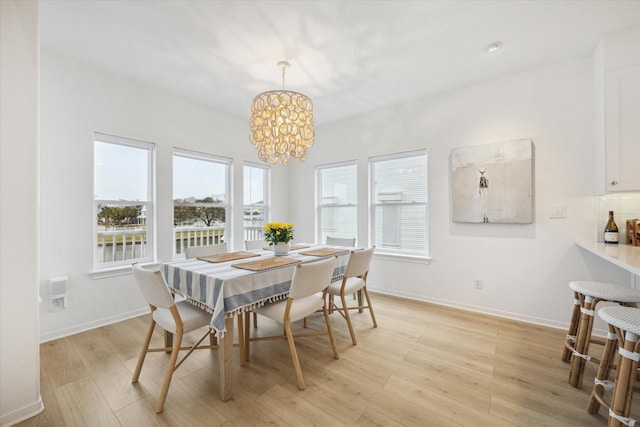 dining room with baseboards, light wood-type flooring, and a notable chandelier