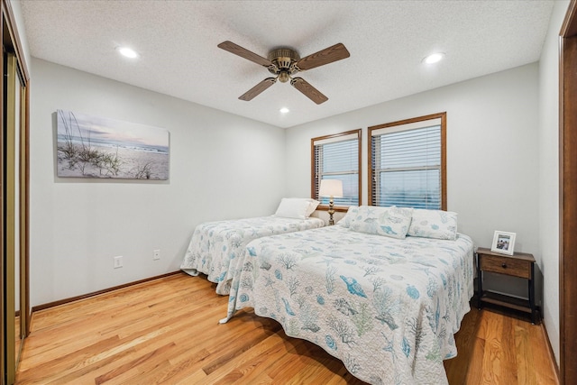 bedroom with a textured ceiling, baseboards, wood finished floors, and recessed lighting