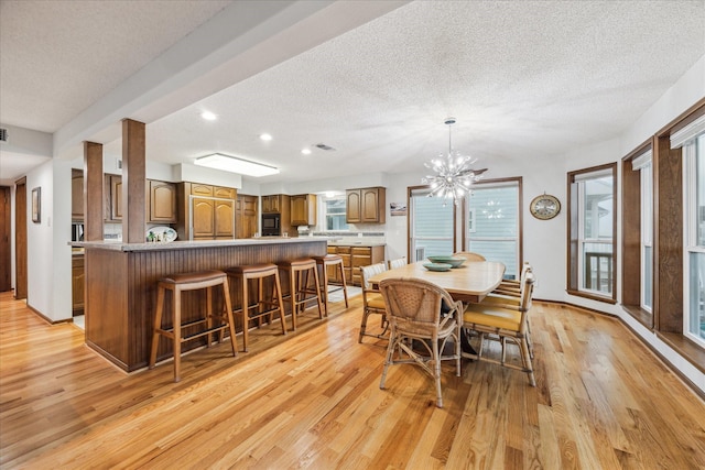 dining space with a textured ceiling, recessed lighting, a notable chandelier, baseboards, and light wood finished floors