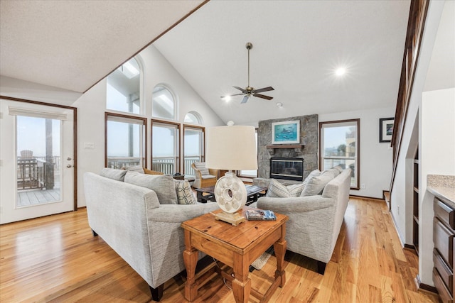 living area with lofted ceiling, light wood-type flooring, a fireplace, and a wealth of natural light