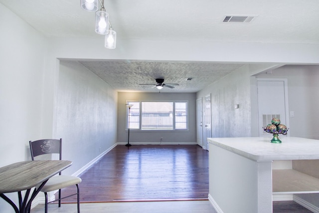 interior space with ceiling fan, a textured ceiling, and dark hardwood / wood-style flooring