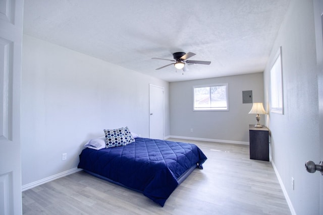 bedroom featuring light wood-type flooring, ceiling fan, and a textured ceiling