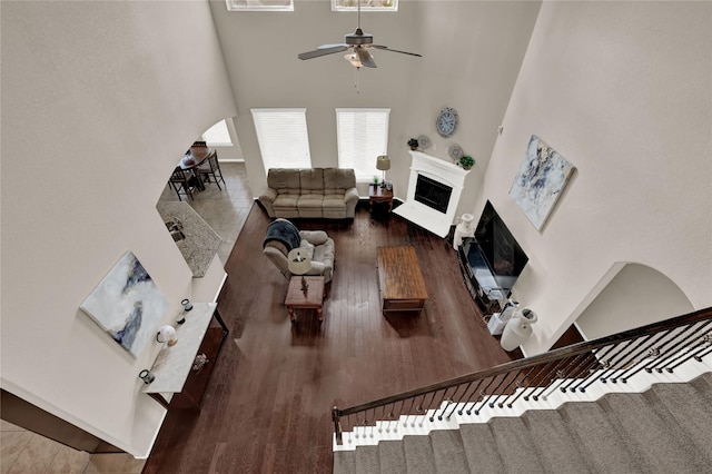 living room with hardwood / wood-style flooring, ceiling fan, and a towering ceiling