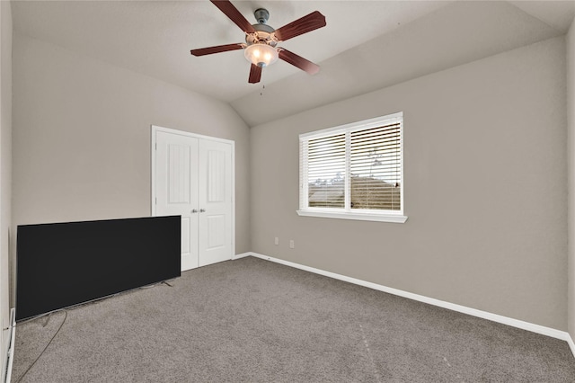 unfurnished bedroom featuring ceiling fan, vaulted ceiling, carpet floors, and a closet