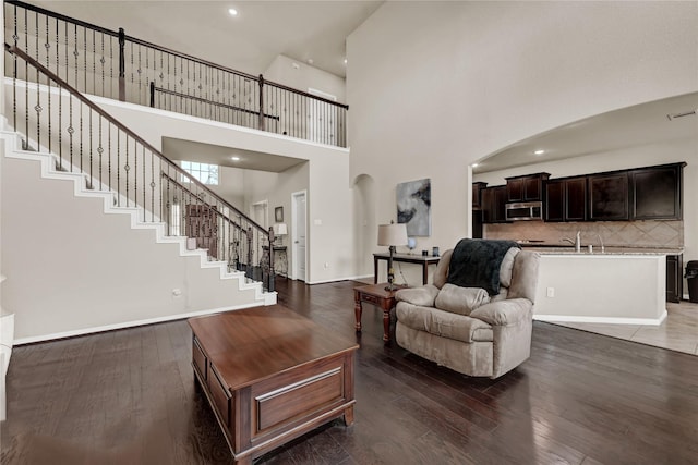 living room featuring a high ceiling, dark wood-type flooring, and sink